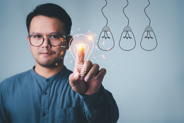 Fototapete - man touching on with idea light bulb front on gray wall background.creative idea.Concept of idea and innovation
