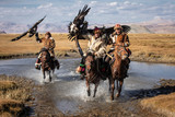 Fototapeta  - A group of traditional kazakh eagle hunters holding their golden eagles on horseback while galloping through a river. Ulgii, Mongolia.