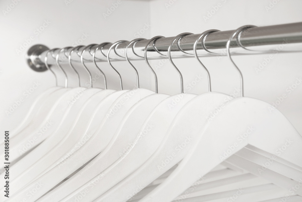 Rack with clothes hangers on white background, closeup