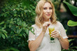 © DragonImages - Beautiful smiling woman enjoying tasty sour lemon lime alcoholic cocktail when walking in garden