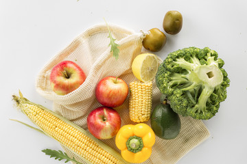 Wall Mural - Full mesh bag of different health food vegetables and fruits on white background top view, flat lay. Clean or eco eating concept