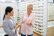 © zinkevych - Young girl helping woman to choose glasses in optical store