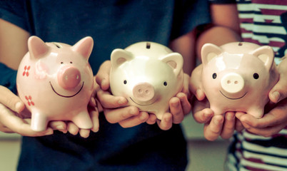 Wall Mural - Saving money - Three kids holding piggy banks