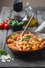 Wall Mural - Penne pasta in tomato sauce and cheese decorated with basil on a wooden background