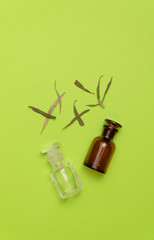 Dried herbs and two empty vials on green background. Herbal medicine. Alternative medicine concept.