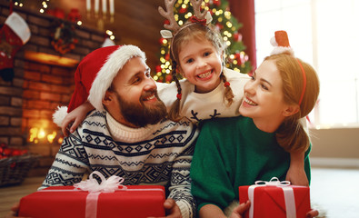 Wall Mural - happy family mother, father and child  with gifts near   Christmas tree at home.