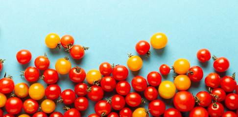 Red and yellow cherry tomatoes on blue background. Fresh bright organic vegetables.