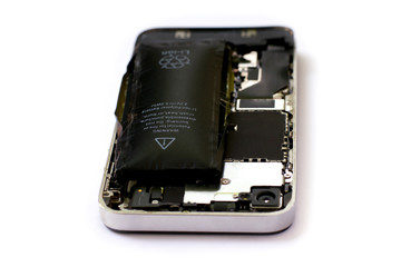 Swollen lithium ion polymer battery inside a mobile phone on white background isolated