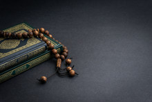 Holy Quran With Arabic Calligraphy Meaning Of Al Quran And Tasbih Or Rosary Beads On Black Background. Selective Focus And Crop Fragment