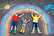 © Irina Schmidt - three little children, two school kids boys and toddler girl having fun with with rainbow picture drawing with colorful chalks on asphalt. Siblings in rubber boots painting on ground playing together.
