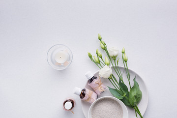 Spa composition with oils, sea salt, candles and a branch of white eustoma on a white background