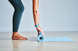 © Kalim - Young woman rolling yoga mat at home