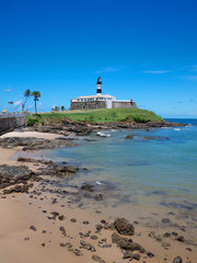 Wall Mural - Bright sunny daytime view of the Farol da Barra lighthouse standing above its colonial fortress on the point in Salvador, Bahia, Brazil 