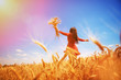 Happy woman enjoying the life in the field Nature beauty, blue sky and field with golden wheat. Outdoor lifestyle. Freedom concept. Woman jump in summer field