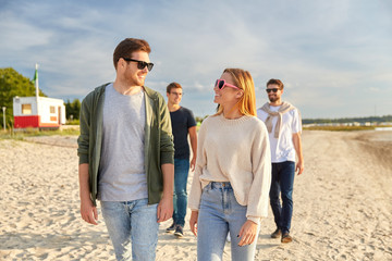 Canvas Print - friendship, leisure and people concept - group of happy friends walking along beach in summer