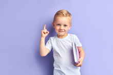 Caucasian Kid Show Bright Emotions Standing Over Purple Background, Holding Purple Notebook.