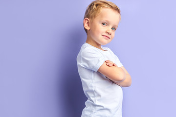 side view on cute little boy posing isolated over purple background, looking at camera. portrait
