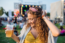 A Young Woman With Drink Dancing At Summer Festival.