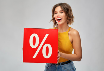 Sticker - shopping, consumerism and people concept - happy smiling young woman in mustard yellow top and jeans with sale signs over grey background