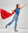 © Syda Productions - women's power and people concept - happy woman in red superhero cape making flying pose over grey background
