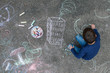 Young boy drawing on the sidewalk with chalk