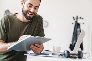 Sticker - Image of smiling young man making notes and holding clipboard