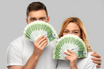 Poster - finance, saving and people concept - portrait of happy couple in white t-shirts with euro money over grey background