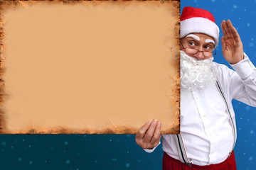 Santa Claus with a beard holds a beautiful blank, blank, old paper poster, cardboard, blank for the designer, pattern for announcements, invitations, greetings, calendar, mock up, close-up, copy space