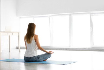 Wall Mural - Young woman practicing yoga at home