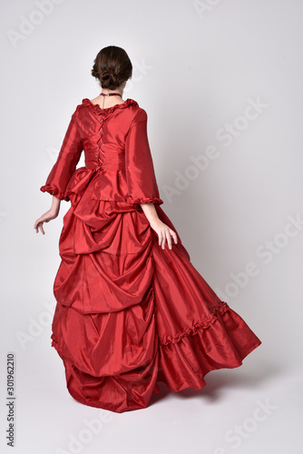 Fotografía full length portrait of a brunette girl wearing a red silk victorian gown