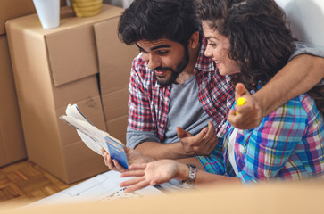 Wall Mural - Happy young couple moving into their new home. They sitting on the floor and choosing colors for the walls.	