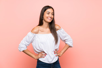 Young woman over isolated pink background posing with arms at hip and smiling