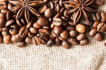 Roasted coffee beans and spice badian on a background of burlap.