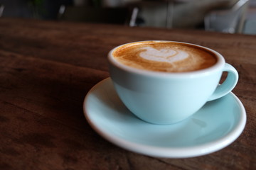 Wall Mural - Cappuccino or latte with frothy foam, blue coffee cup top on wooden coffee shop background