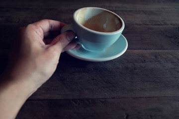 hands holding hot cup of coffee on rustic wooden table background