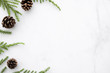 © satapatms - White marble table with Christmas decoration including pine branches and pine cones. Merry Christmas and happy new year concept. Top view with copy space, flat lay.