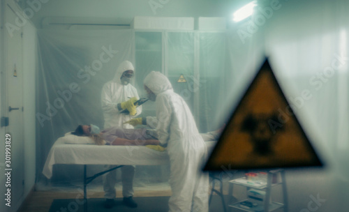 Fotografía Two people attending to a woman with a virus lying on a stretcher in a field hos