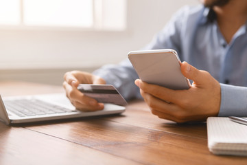 Businessman paying his bills online with smartphone and credit card