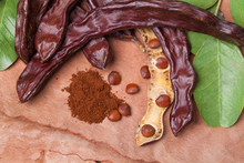 Carob. Organic Carob Pods With Seeds And Leaves On Tree Bark Table. Healthy Eating, Food Background.
