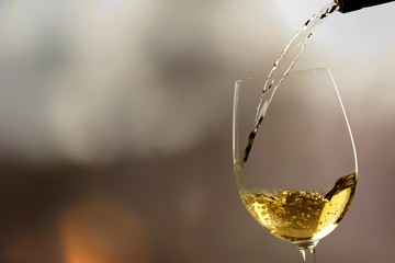 Canvas Print - White wine being poured in wineglass, closeup