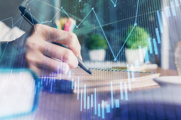 Financial forex charts displayed on woman's hand taking notes background. Concept of research. Double exposure