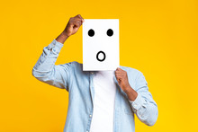 Black Guy Hiding Face Behind Paper With Drawn Surprised Emoticon