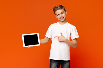 Cool teenage boy pointing at blank screen of digital tablet