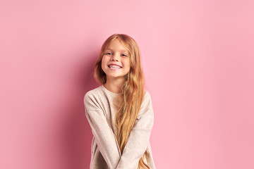portrait of positive cheerful girl cutely smiling at camera, girl with long golden hair in white blo