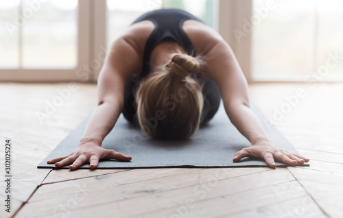 Fotomural Blonde woman laying face down on yoga mat, stretching