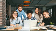 © Prostock-studio - College students studying together in library, using laptop