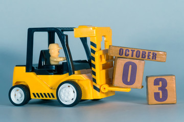 october 3rd. Day 3 of month, Construction or warehouse calendar. Yellow toy forklift load wood cubes with date. Work planning and time management. autumn month, day of the year concept