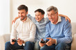 © Prostock-studio - Elderly Man, Mature Son And Grandson Playing Videogame At Home