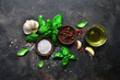 Culinary background with traditional italian spices : basil, garlic, sea salt, pepper and olive oil. Top view with copy space.