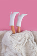 Doll's legs sticking out from under synthetic white fur. Minimalism concept, 80s style. Happy holidays greeting card